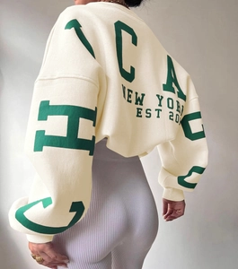 Detail of the green Chicago and New York text print on the back of an ivory sweatshirt