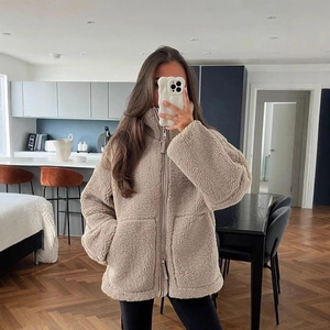Women's oversized beige lamb wool jacket with high collar and zipper in minimalist style