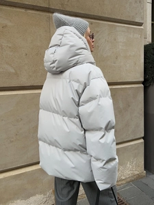 Detailed side view of an oversized light gray hooded puffer jacket with quilted stitching