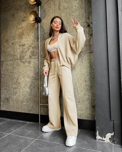 Detailed view of beige zip-up bomber jacket and wide-leg trousers set on a model