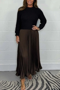Detail of black knit top paired with shiny pleated maxi skirt in bronze finish