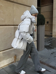 Detail of light grey oversized hooded puffer jacket with matte finish and urban style