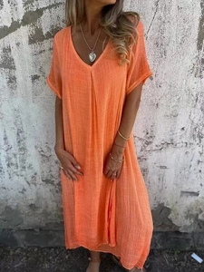 Détail du col en V et de la texture plissée en coton et lin sur une robe longue orange