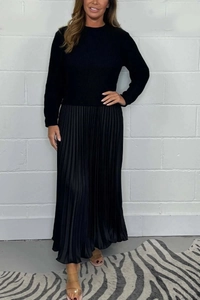 Detail of a solid black long sleeve knit dress with an elegant pleated maxi skirt texture