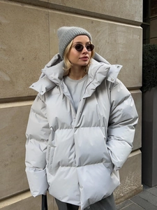 Detail of light grey hooded puffer jacket featuring a windproof brim and silver metal snaps