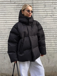 Detail of oversized black hooded puffer jacket with premium matte texture and warm filling