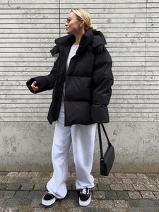 Detailed view of oversized matte black hooded jacket paired with casual street style wear