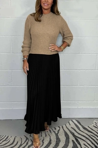 Detailed texture of brown long-sleeved knit top paired with black high-waisted pleated skirt