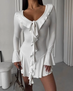 Détail de robe blanche à volants avec décolleté en V profond et lacets sur le devant