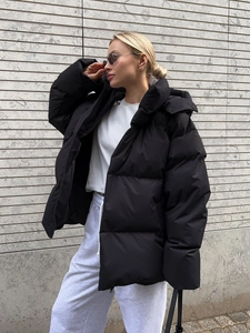Outdoor shot of a woman in a black hooded puffer jacket with loose fit for winter