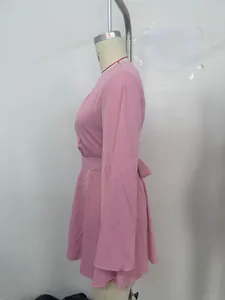 Vue détaillée d'une robe rose à manches longues évasées avec un nœud papillon à la taille