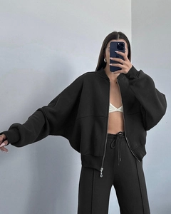 Detailed close-up of black zip-up cropped jacket with ribbed cuffs and matching joggers