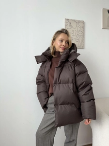 Detail of oversized dark brown quilted winter jacket with hood and puffer texture