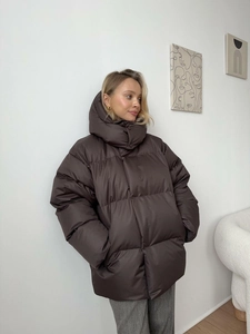 Detail view of a loose-fitting brown winter puffer jacket with hood for women outdoors
