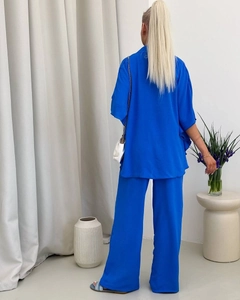 Back view of elegant royal blue two-piece set featuring long shirt and wide-leg trousers