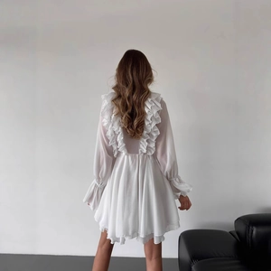 Detail view of white chiffon dress featuring layered vertical ruffles and smocked cuffs