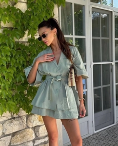 Detail of mint green lapel dress with waist tie and layered skirt in an elegant outdoor setting