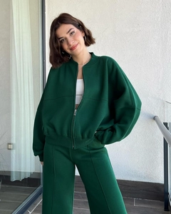 Detail of dark green tracksuit featuring metal zipper jacket and pleated wide-leg pants