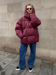 Outdoor shot of an oversized dark red hooded puffer jacket with warm quilted layers