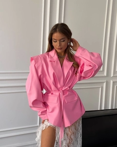 Detail of pink blazer featuring structured shoulder pads and matching waist tie belt