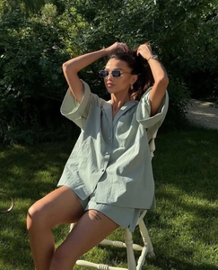 Detail of light green two-piece linen set with button-down shirt and loose shorts