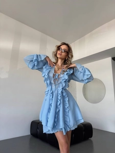 Detail of light blue chiffon dress featuring V-neckline with delicate self-tie bow and ruffles
