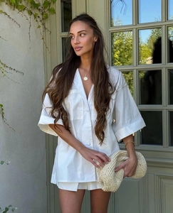 Detail of white linen set featuring large lapels, button closure and square pockets on shirt
