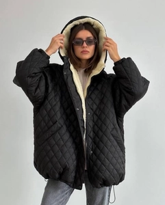 Detail of black quilted hooded jacket with soft cream fleece lining and snap buttons