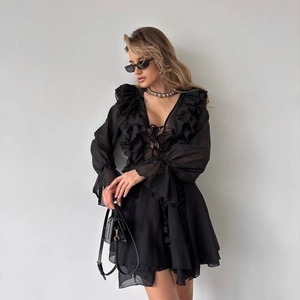 Close-up of black chiffon dress with V-neck lace-up detail and romantic ruffle accents