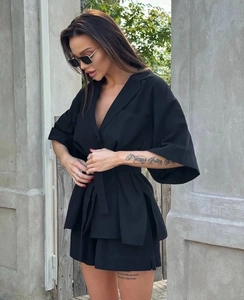 Detail of black two-piece set featuring belted waist, lapel collar, and side slit shorts