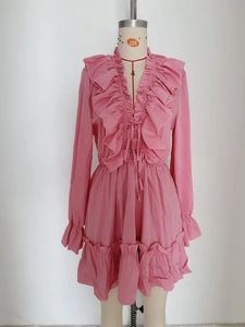 Detail of V-neckline with layered ruffles and flared cuffs on pink dress