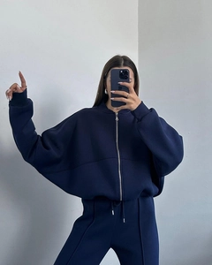 Detail of navy blue tracksuit showing zippered sweatshirt and pants with front pleats