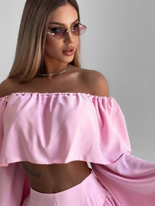 Detailed shot of pink satin off-shoulder top with ruffled neckline and loose sleeves