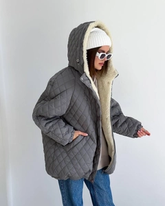Detail view of women's grey quilted hooded jacket with soft faux lamb wool lining texture