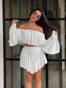 Elegant white two-piece set featuring an off-shoulder ruffled top and pleated mini skirt