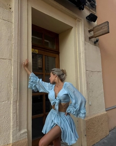 Detail of sky blue two-piece set featuring V-neck tie crop top and pleated mini skirt
