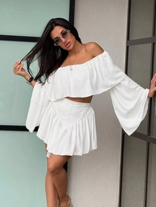 Detail view of white off-shoulder ruffle top and high waist pleated mini skirt set