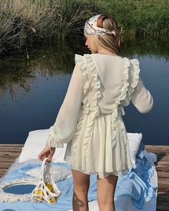 Detail eines cremefarbenen Chiffonkleides mit Rüschen und ausgestellten Ärmeln am See
