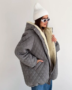 Detail of grey diamond-quilted parka featuring thick cream faux shearling lining and metal snaps