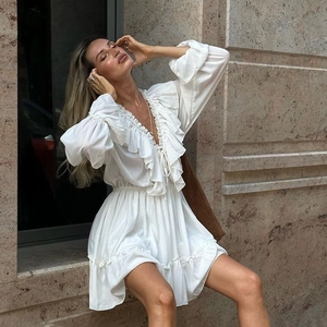 Detail of elegant white V-neck dress featuring ruffled tiers and tied drawstring neckline