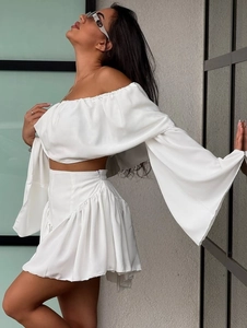 Elegant white two-piece set featuring off-shoulder long sleeve top and high waist pleated skirt