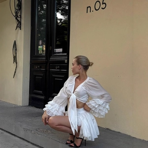 Detail of white two-piece set featuring V-neck tie-front top and pleated mini skirt