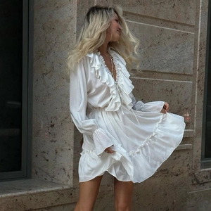 Close-up of white dress detailing the deep V-neckline with delicate ruffled edge