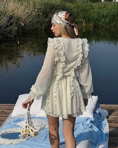 Detail des weißen Langarmkleides mit eleganten Rüschenlagen und Taillierung