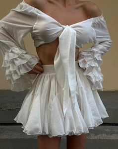 Detailed view of white pleated mini skirt and layered ruffle sleeve texture of the outfit