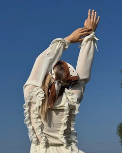 Detail eines eleganten cremeweißen Chiffonkleids mit Volants und Vintage-Seidenkopftuch