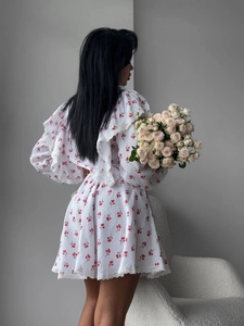 Detailed view of white floral dress with red cherry prints and lace collar trim