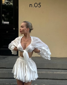 Detail of white two-piece set featuring a tie-up V-neck top with ruffled tiered sleeves