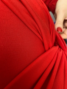 Close-up of bright red cotton bodysuit showing twist detail and ribbed texture