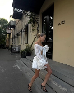 Detail of white off-shoulder top with tiered ruffle skirt and large bow accent